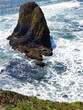The rugged cliffs at Yaquina Head  with the blue waters of the Pacific Ocean crashing into them on the Central Oregon Coast on a sunny spring day.
