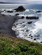 The rugged cliffs at Yaquina Head  with the blue waters of the Pacific Ocean crashing into them on the Central Oregon Coast on a sunny spring day.