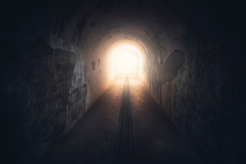 Light in end of tunnel. Long underground concrete corridor in abandoned bunker, toned