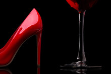 A Glass Of Red Wine And Women's Shoes With Heels. Red High-heeled Shoes And A Glass Of Wine.