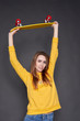© Kiryl Lis - Portrait of positive young attractive girl wearing yellow blouse and blue jeans holding yellow skateboard.