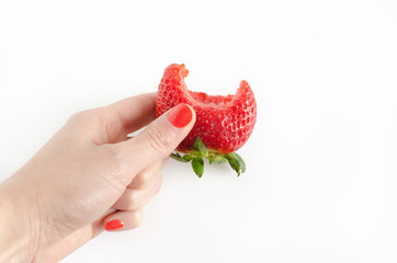 Strawberry bitten in woman's hand.