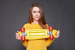 © Kiryl Lis - Portrait of positive young attractive girl wearing yellow blouse and blue jeans holding yellow skateboard.