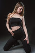 © Антон Фрунзе - Young beautiful, slender, passionate brown-haired woman with bright red lips and long hair in a black top and denim shorts on a dark background