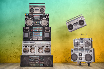 Poster - Retro old design ghetto blaster boombox radio cassette tape recorders tower from circa 1980s, handcart front aged colored concrete wall background conceptual composition. Vintage style filtered photo