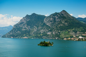 Loreto island in the middle of the Iseo lake with montains in the background