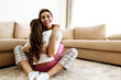 Family. Love. Togetherness. Mom and daughter in pajamas are hugging and smiling while sitting on the floor at home