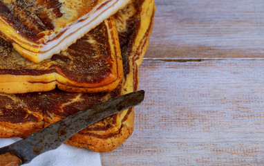 Delicious smoked bacon on wooden table of traditional smoked meats