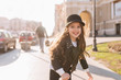 Inspired cute child with long dark hair playing on the street in good mood, waiting for friends and smiling. Portrait of pretty little girl in leather jacket posing on blur background in morning.