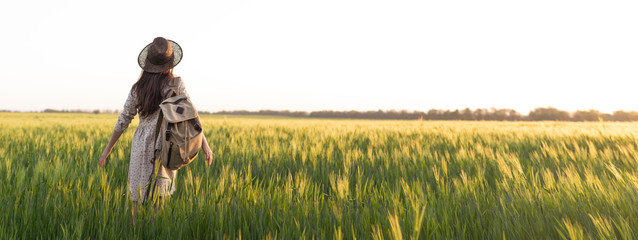 Freedom. Traveler with a backpack in a field of wheat. Happy woman outdoors with her hands open