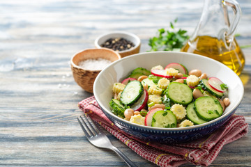 Wall Mural - Healthy vegetable salad with cucumber, radish, beans, mini corn and herbs on rustic wooden background. Selective focus.