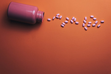 Poster - Beautiful pink bottle and pink pills on a beautiful coral orange background.