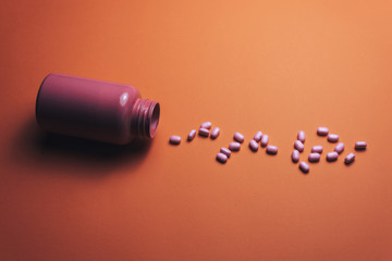 Poster - Beautiful pink bottle and pink pills on a beautiful coral orange background.