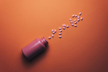 Poster - Beautiful pink bottle and pink pills on a beautiful coral orange background.