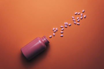 Poster - Beautiful pink bottle and pink pills on a beautiful coral orange background.