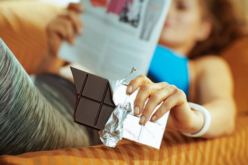 Wall Mural - Closeup on chocolate bar in hands of woman laying on sofa