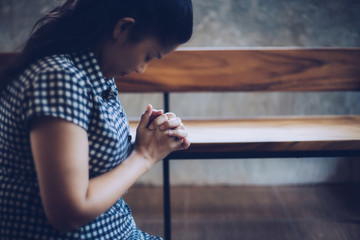 Wall Mural - portrait of an Asian woman is praying to God indoor with window light. Christian background faith and trust concept.