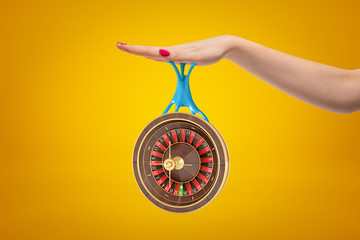 Poster - Side crop closeup of woman's hand holding casino wheel that is hanging down on blue sticky slime stuck to her palm.