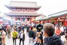 Sensoji Temple In Tokyo, Japan Asakusa With Red Architecture And Crowd Of People By Incense Smoke And Man Photographer Videographer Filming With Camera And Gimbal