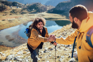 helping hand - hiker man getting help on hike happy overcoming obstacle.