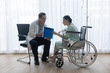 © kokotewan - The senior male doctor talked and inquired about the patient's illness at the wheelchair of the patient.
