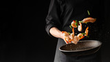 Fototapeta Miasto - Seafood, Professional cook prepares shrimps with sprigg beans. Cooking seafood, healthy vegetarian food and food on a dark background. Horizontal view. Eastern kitchen