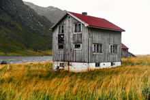 Old Damaged Wooden Norwegian House With A Red Corrugated Iron Rooftop In The Village Vinstad On Lofoten Islands In Norway.