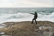 © Julian - Young man standing on cliffs in front of the wild ocean with waves clashing against the rocks at Bunes Beach on Lofoten Islands in Norway