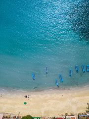 Wall Mural - Aerial : beach aerial view on the sea waves against the sand beach line and overhead view of a water jet scooter rental point  and  thai taxi boats parking