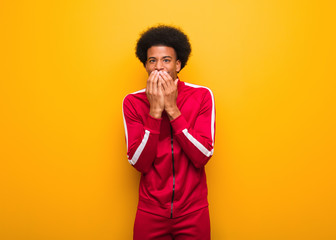 Wall Mural - Young sport black man over an orange wall laughing about something, covering mouth with hands