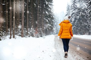 Wall Mural - Beautiful young woman near road in winter forest