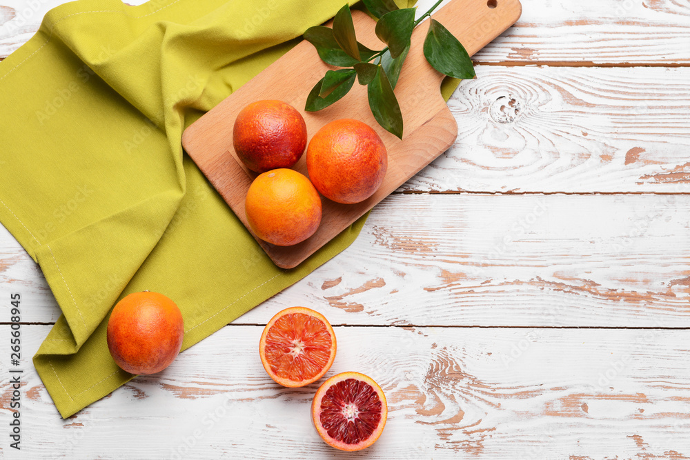 Cutting board with fresh blood oranges on white table