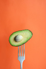 Wall Mural - Avocado on a fork. Orange background with empty space