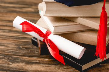 Wall Mural - diploma with ribbon and stack of books on wooden surface