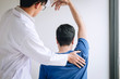 Doctor physiotherapist assisting a male patient while giving exercising treatment massaging the shoulder of patient in a physio room, rehabilitation physiotherapy concept