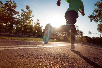 Runner feet running on road closeup on shoe. Young athlete on sunset run at park