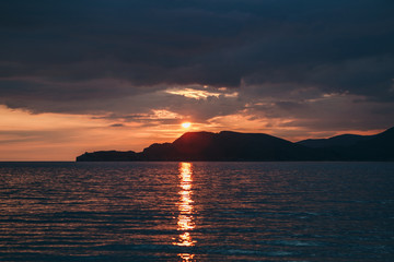 Beautiful view of the sunset or sunrise and the natural landscape with the sea and hills or mountains in Montenegro in the summer.