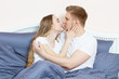 © paulcannoby - Beautiful loving couple kisses and hugging on bed in the morning.