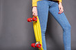 © Kiryl Lis - Girl wearing yellow blouse and blue jeans holding yellow skateboard.