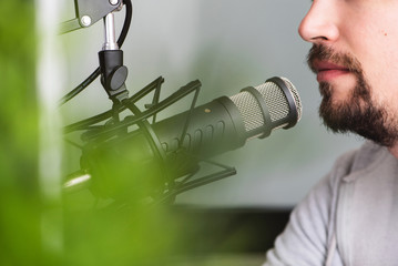 Attractive Young Man speaking Into Microphone. Man and podcast host Talking to Microphone.