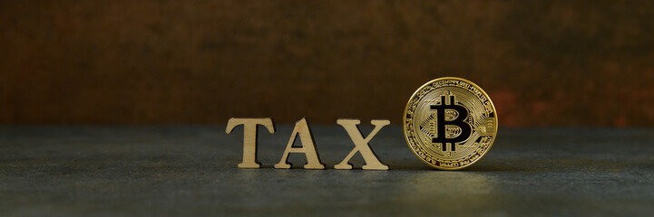 Bitcoin and wooden letters TAX on stone background