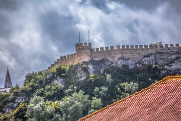 View of the fortress and Luso Roman castle of Óbidos, with buildings of Portuguese vernacular architecture and sky with clouds, in Portugal