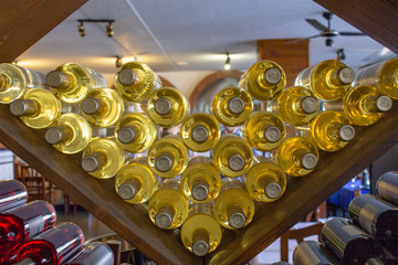 Bottles of white and red wine on a wooden shelf with books in private winery cabinet room interior