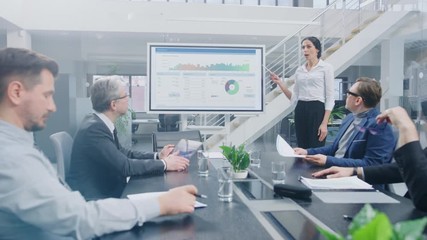 Wall Mural - In the Corporate Meeting Room: Female Analyst Uses Digital Interactive Whiteboard for Presentation to a Board of Executives, Lawyers, Investors. Screen Shows Company Growth Data with Animated Graphs