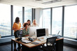 © Monkey Business - Four female creatives working around a computer monitor in an office, full length view