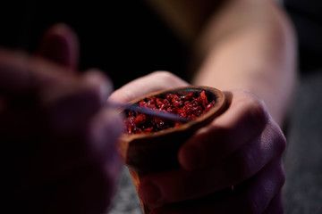 Barman fills black burnt ceramic bowl for hookah smoking different types of tobacco.