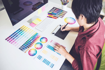 Poster - High angle view of female graphic designer working on color selection and drawing on graphics tablet at workplace