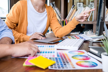 Poster - Two colleague creative graphic designer working on color selection and color swatches, drawing on graphics tablet at workplace with work tools and accessories