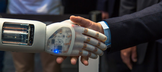 Friendship between human and robot - Business Human and Robot hands in handshake. Artificial intelligence technology Design Concept. Friendship between Artificial and real man conceptual template.