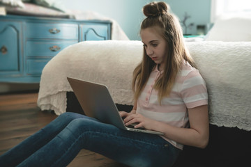 Wall Mural - A Young smiling teen girl on bed with laptop